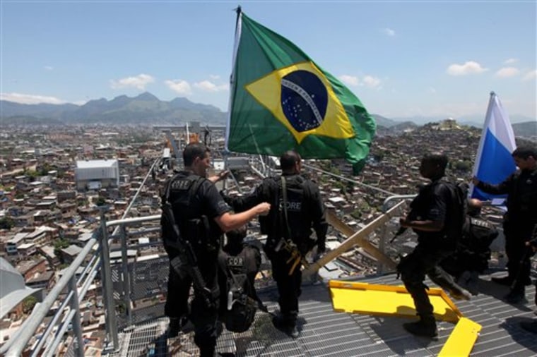 Police officers place a Brazilian flag atop the Complexo do Alemao slum in Rio de Janeiro, Brazil, on Sunday. 